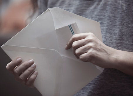 Picture of someone opening letter. Credit: Plainpicture